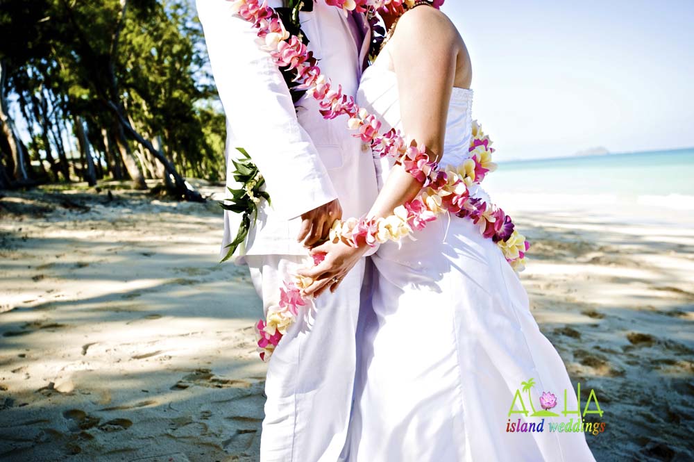 tied with the love of flower leis around them at the Hawaiian wedding